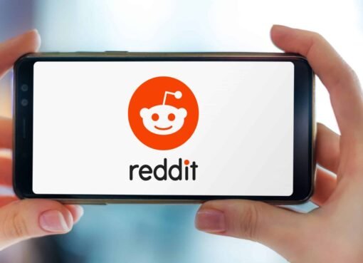 Mãos segurando um smartphone exibindo o logotipo do Reddit, um site americano de agregação de notícias sociais, classificação de conteúdo da web e discussão